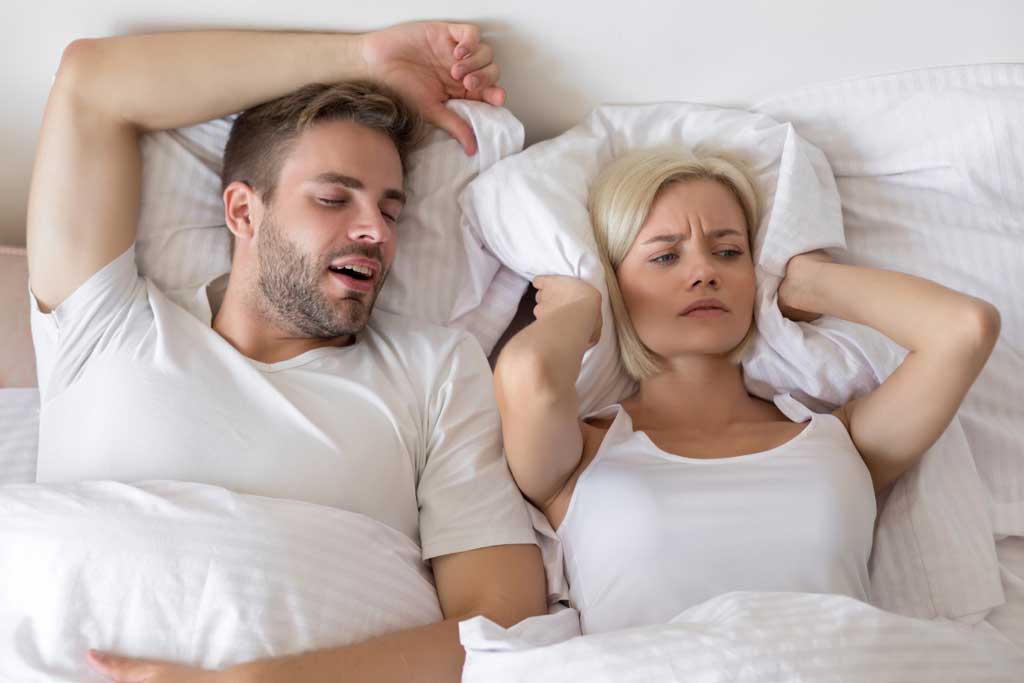 Snoring-man-in-bed-while-woman-struggles-to-sleep