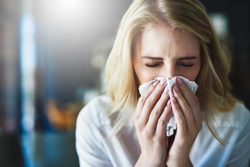 Woman-blowing-her-nose-into-a-tissue-and-experiencing-blocked-sinuses,-a-symptom-of-chronic-sinusitis