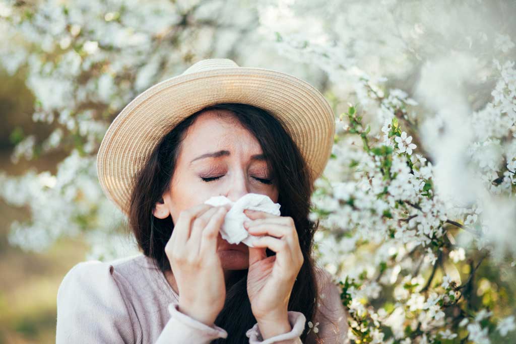 Woman-blowing-her-nose-near-a-blossom-tree-suffering-from-allergy-and-nasal-turbinate-hypertrophy