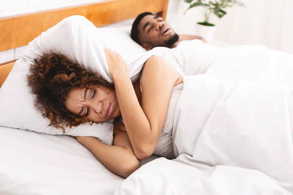 Woman-is-struggling-to-sleep-as-her-husband-snores,-a-symptom-of-obstructive-sleep-apnea