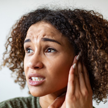 Woman-touching-her-ear-in-pain-and-experiencing-symptoms-of-chronic-tonsillitis Woman-touching-her-ear-in-pain-and-experiencing-symptoms-of-chronic-tonsillitis
