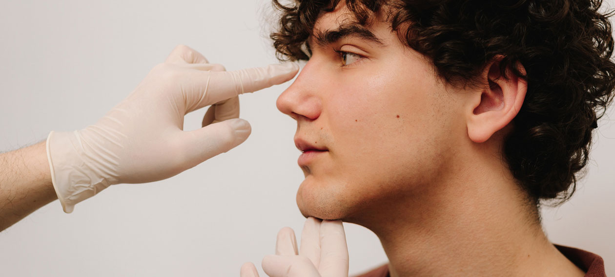 gloved-provider-examining-a-young-man's-nose-in-profile