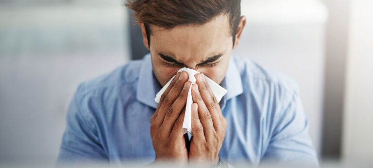 man-blowing-nose-in-business-setting